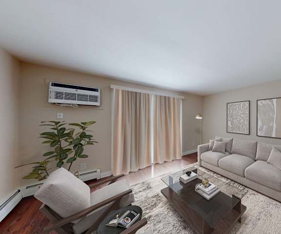 A living room with a grey couch, a coffee table, a plant, and a television.