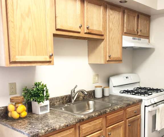 A kitchen with a white stove and wooden cabinets.