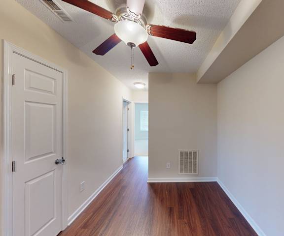 A room with a ceiling fan and wooden floors.