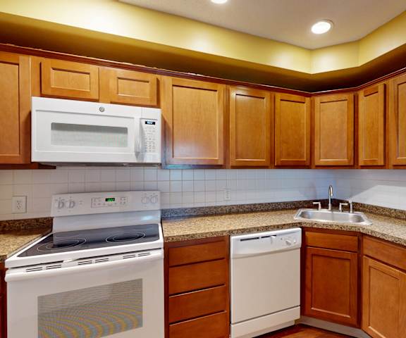 A kitchen with wooden cabinets and a white microwave above the stove.