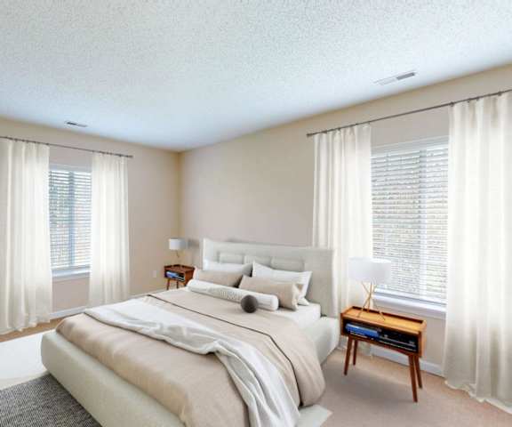 A bedroom with a large bed and a nightstand with a lamp.