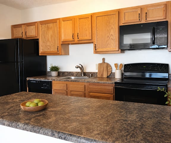 A kitchen with black appliances and wooden cabinets.