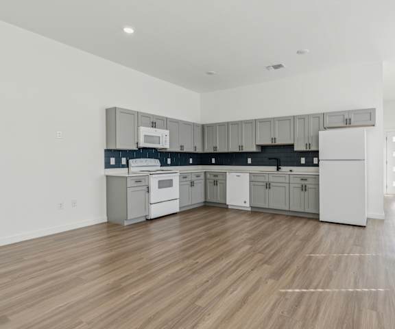 A kitchen with white cabinets and a wooden floor.