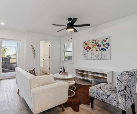 A living room with a white couch, a chair, and a painting on the wall.