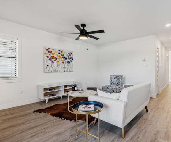 A living room with a white couch, a coffee table, and a painting on the wall.