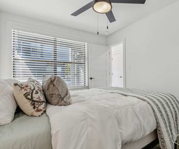 A bedroom with a bed, pillows, and a ceiling fan.