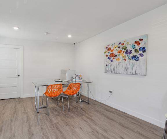 A dining room with a white table and orange chairs.