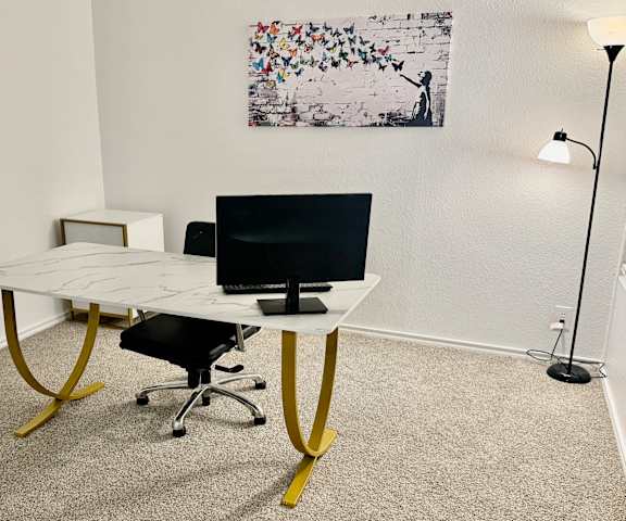A white desk with a black monitor and a yellow chair in a room.