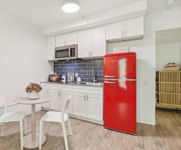 a small kitchen with a red refrigerator and a table and chairs