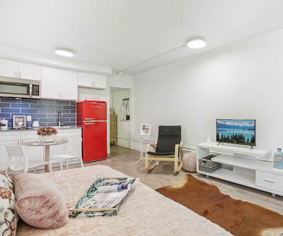 a living room with a couch and a kitchen with a red refrigerator