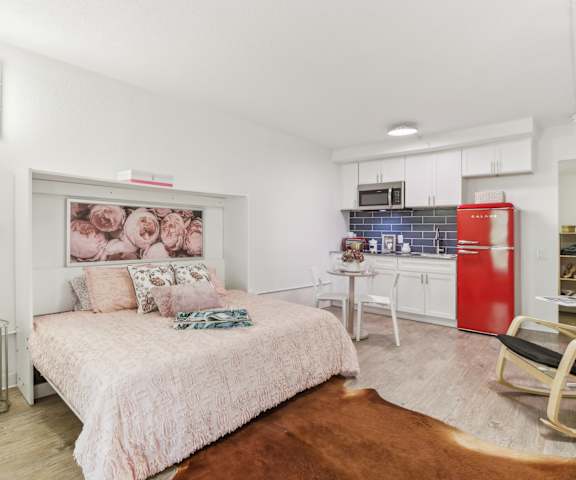 a bedroom with a bed and a kitchen with a red refrigerator