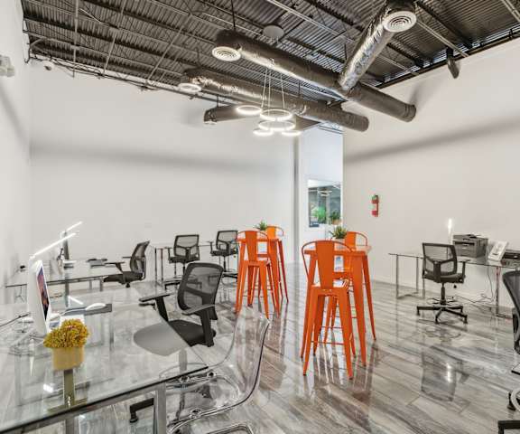 a seating area with chairs and tables in a room with pipes on the ceiling