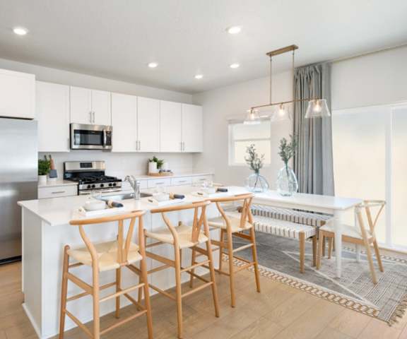A modern kitchen with a white island and wooden chairs.