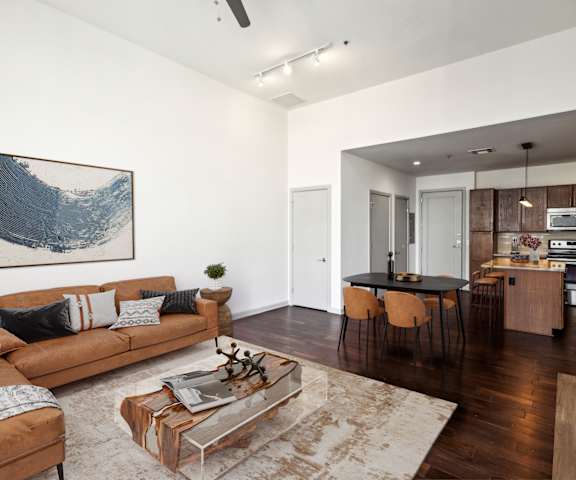 A living room with a brown couch and a painting on the wall.