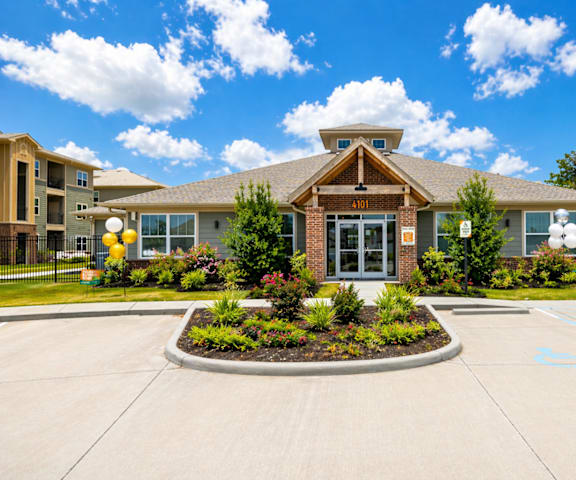 A building with a front yard and a parking lot in front.