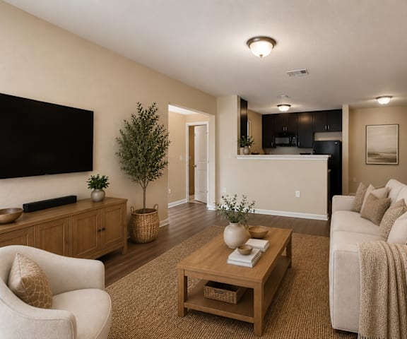 A living room with a white couch, a wooden coffee table, and a flat-screen TV mounted on the wall.