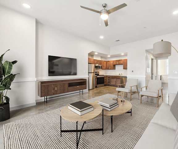 A living room with a white couch, a coffee table, and a television.