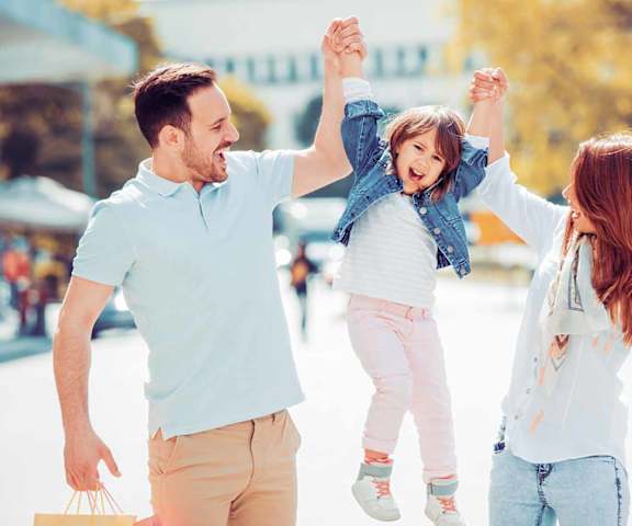 Man and woman lifting child by her arms