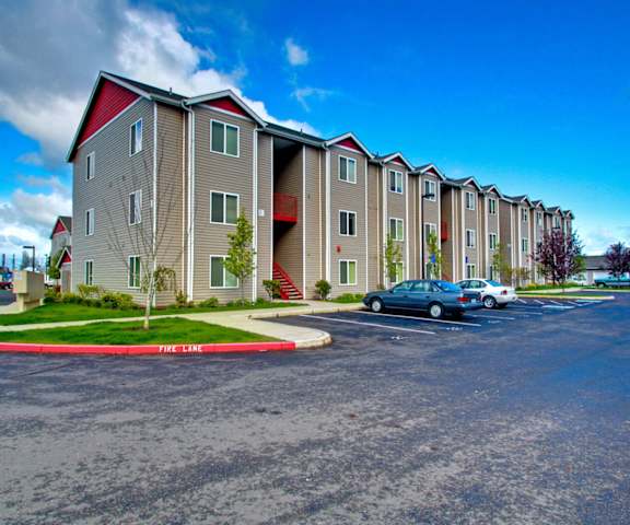 A parking lot in front of a building with a red and white striped walkway.
