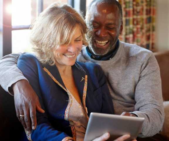 stock image- senior couple on couch with tablet
