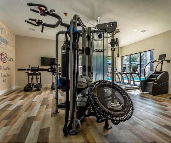 the home gym has plenty of equipment and a view of the pool