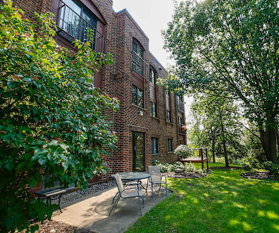 a patio with a table and chairs in front of a brick building