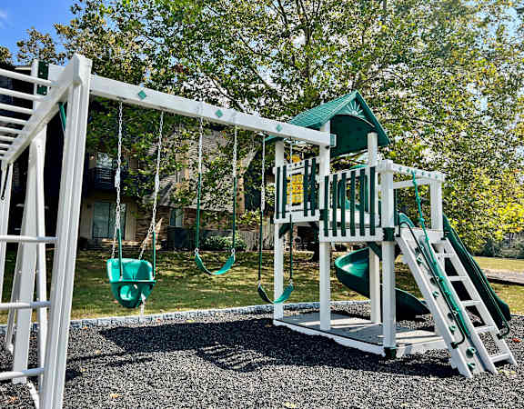a playground with a swing set and a play house