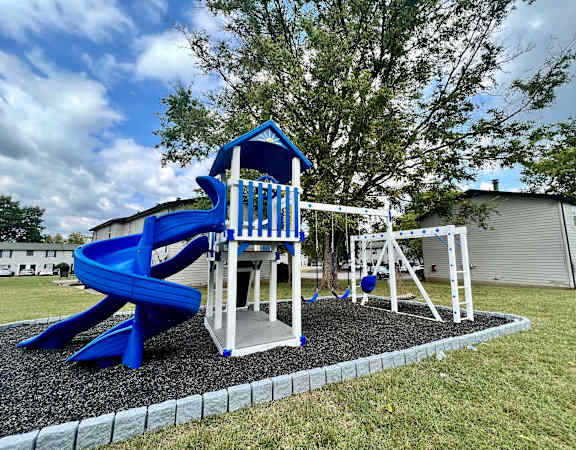 a playground with a blue slide and swing set