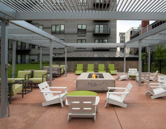 A patio with white chairs and a fire pit.