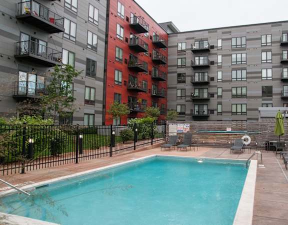 A small pool in a courtyard surrounded by chairs and umbrellas.