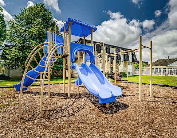 A playground with a blue slide and a wooden structure.