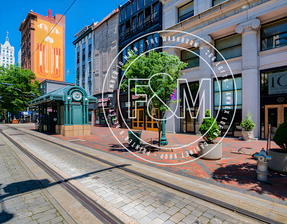 a city street with a tram track in the foreground and a large fm radio in the