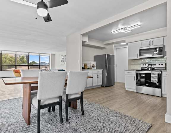 a dining area with a table and chairs and a kitchen in the background