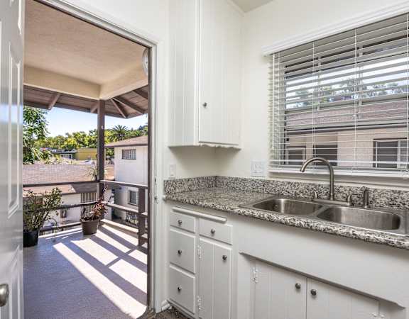 a kitchen with a sink and a window and a door to a balcony