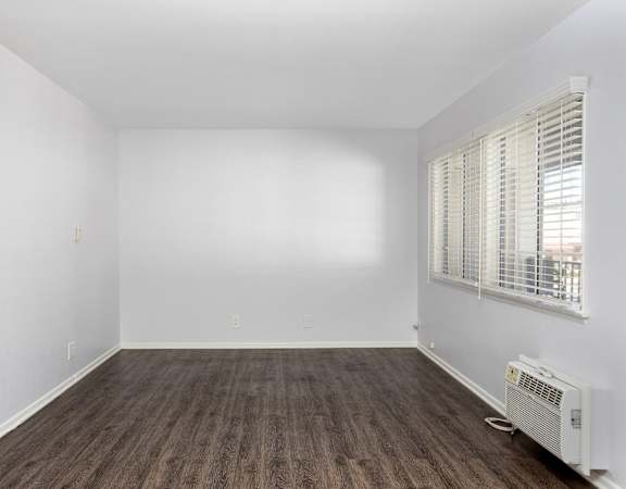an empty room with white walls and wood floors and a window