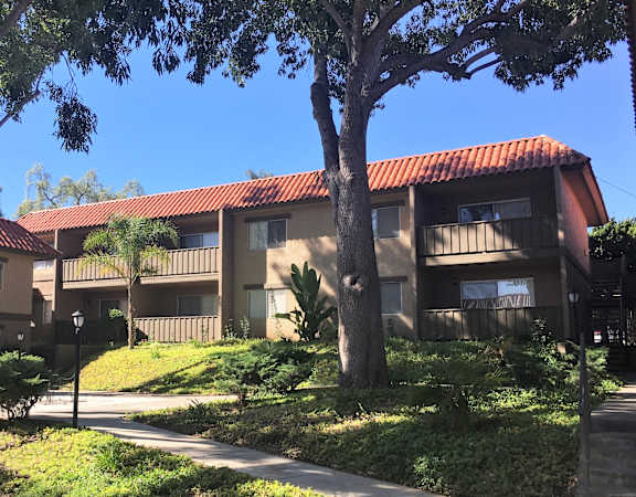 a building with a red tile roof and a sidewalk in front of it