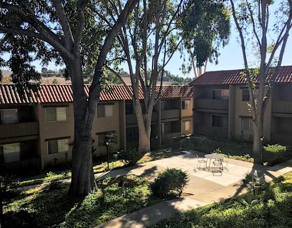 a courtyard with a table and chairs in front of an apartment building