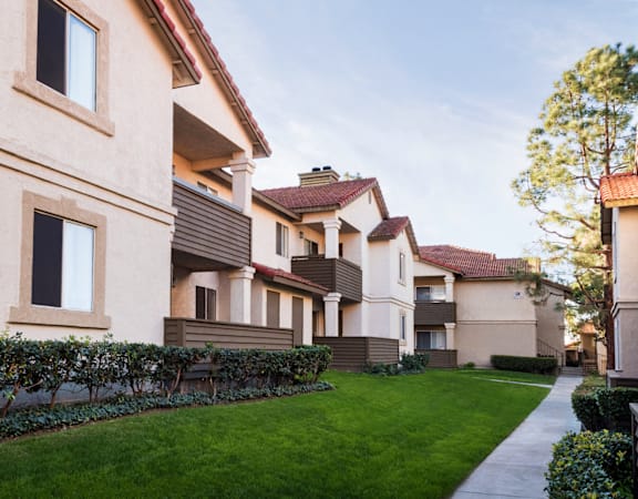 a row of apartment buildings with a green lawn in the foreground