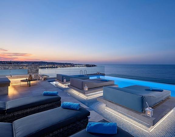 a swimming pool next to the ocean at dusk