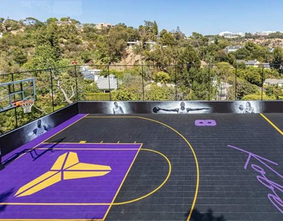 a backyard basketball court with a view of trees and a city