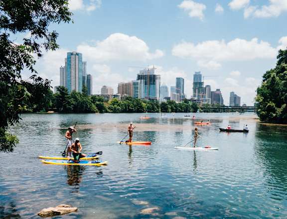 a group of people on kayaks on a lake with a city in the background