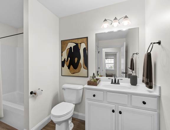 A white bathroom with a toilet, sink, and mirror.