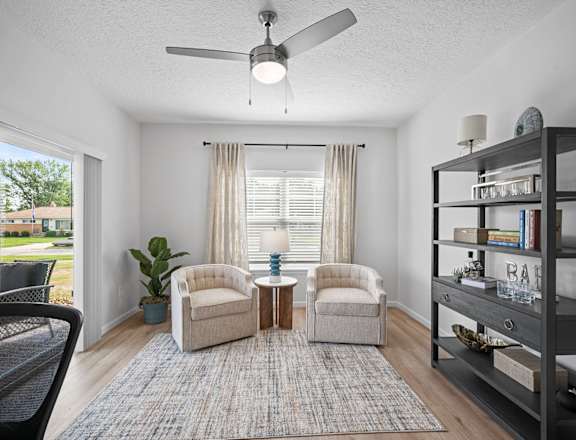 a living room with two chairs and a ceiling fan