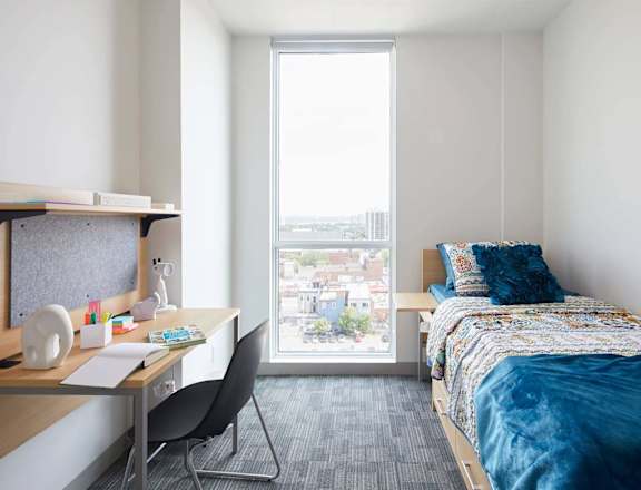 A bedroom with a bed, desk, and chair.
