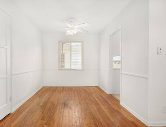 a living room with white walls and wood floors and a window