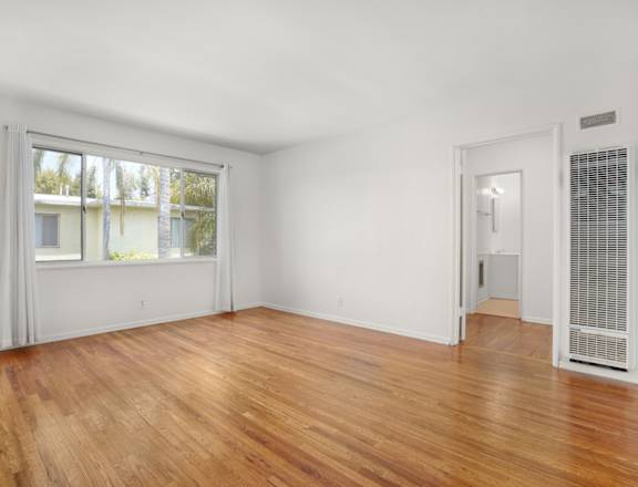 an empty living room with wood floors and a large window