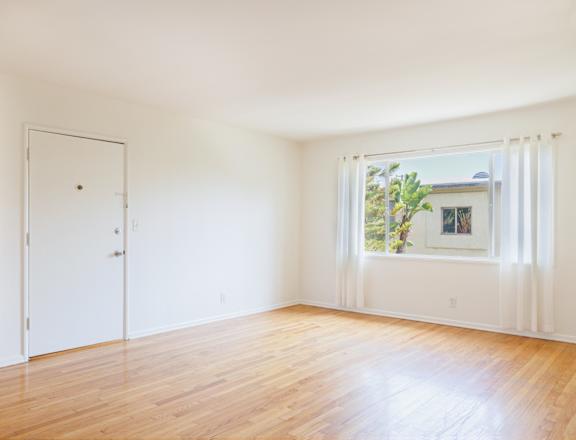 an empty room with white walls and a window and wood floors