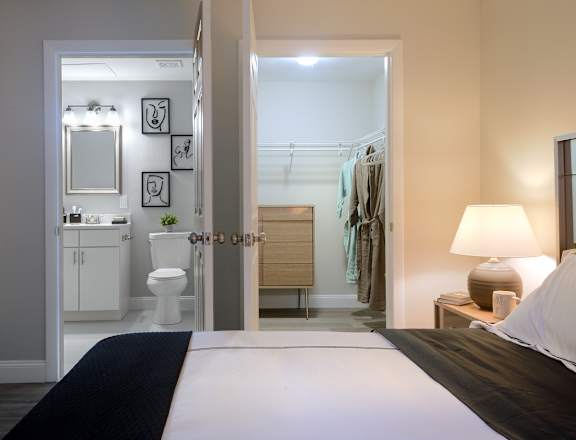 a bedroom with a large bed and a bathroom in the background