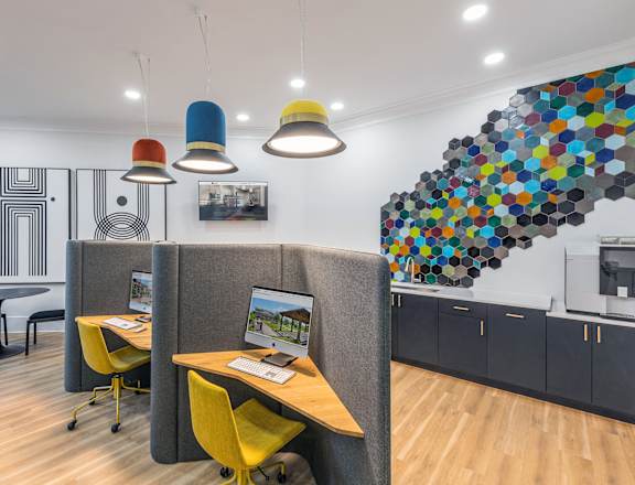 a room with a desk with a computer and chairs and a staircase