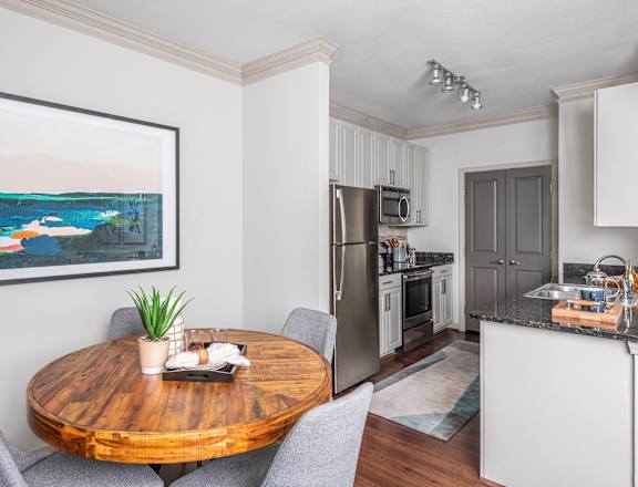 a dining room with a table and chairs and a kitchen with stainless steel appliances